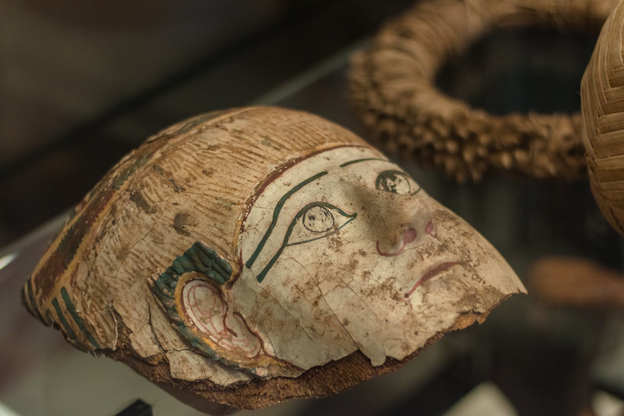 Close-up of an ancient Egyptian mask displayed in a museum exhibit.