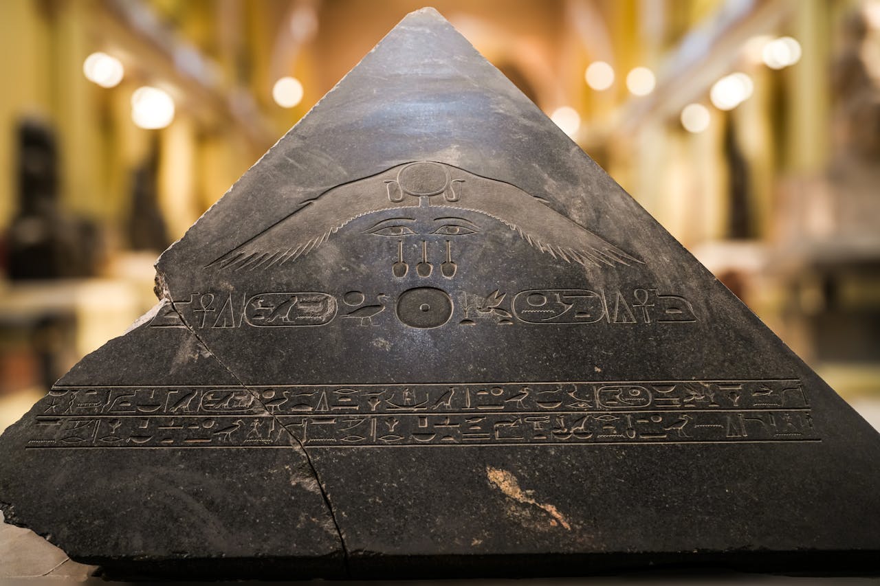 Close-up of a pyramidion with ancient Egyptian hieroglyphs featuring symbolic carvings.