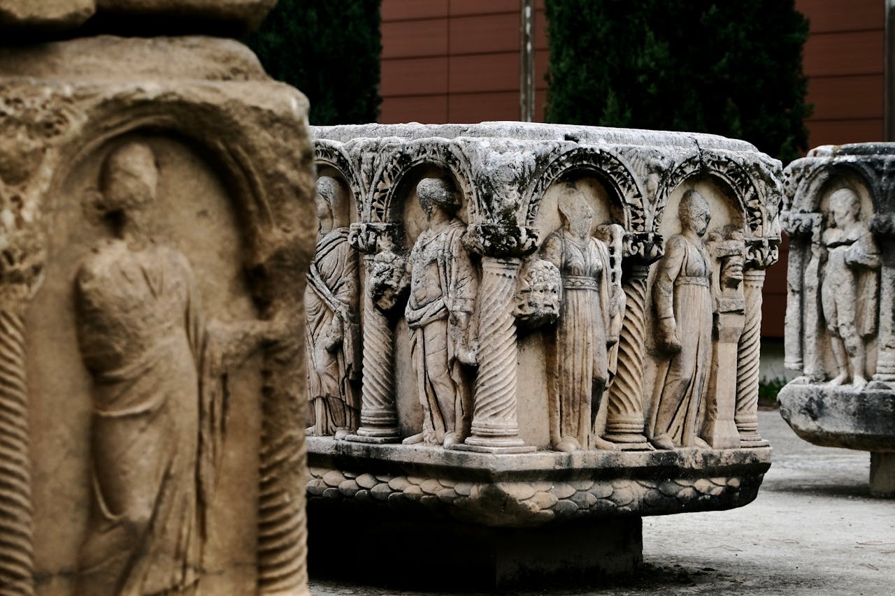 Detailed stone carvings of ancient Roman figures displayed outdoors in a museum setting.
